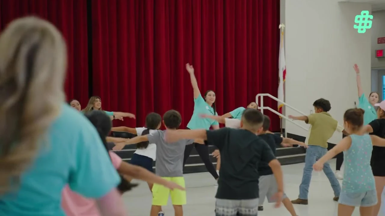 Mentors leading students in a group movement activity indoors