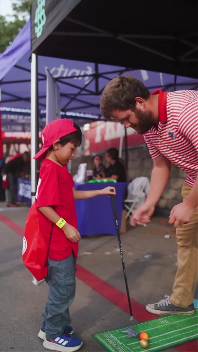 A mentor helping a child with a putting activity at the Offseason Fresno activation