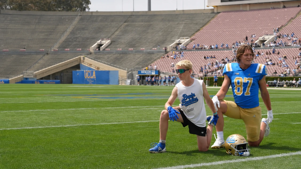 A student and UCLA football player stretching side by side on the Rose Bowl field